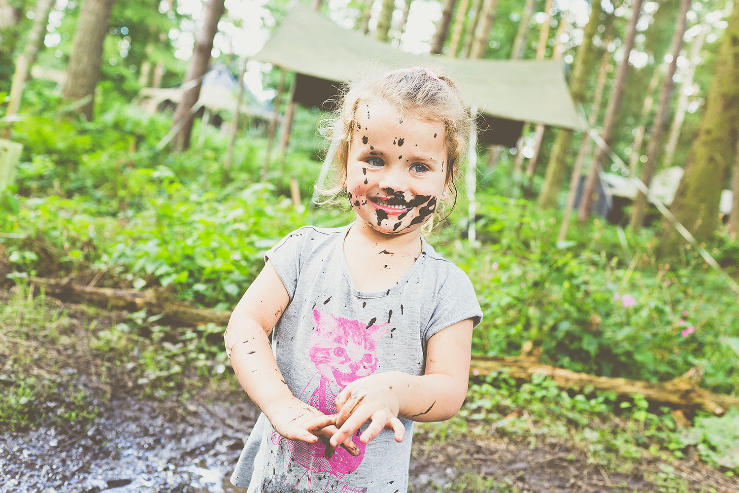 A small child with mud on her face.