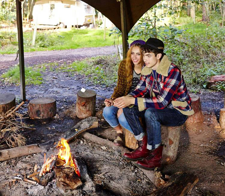 Two people sitting by an open flame.