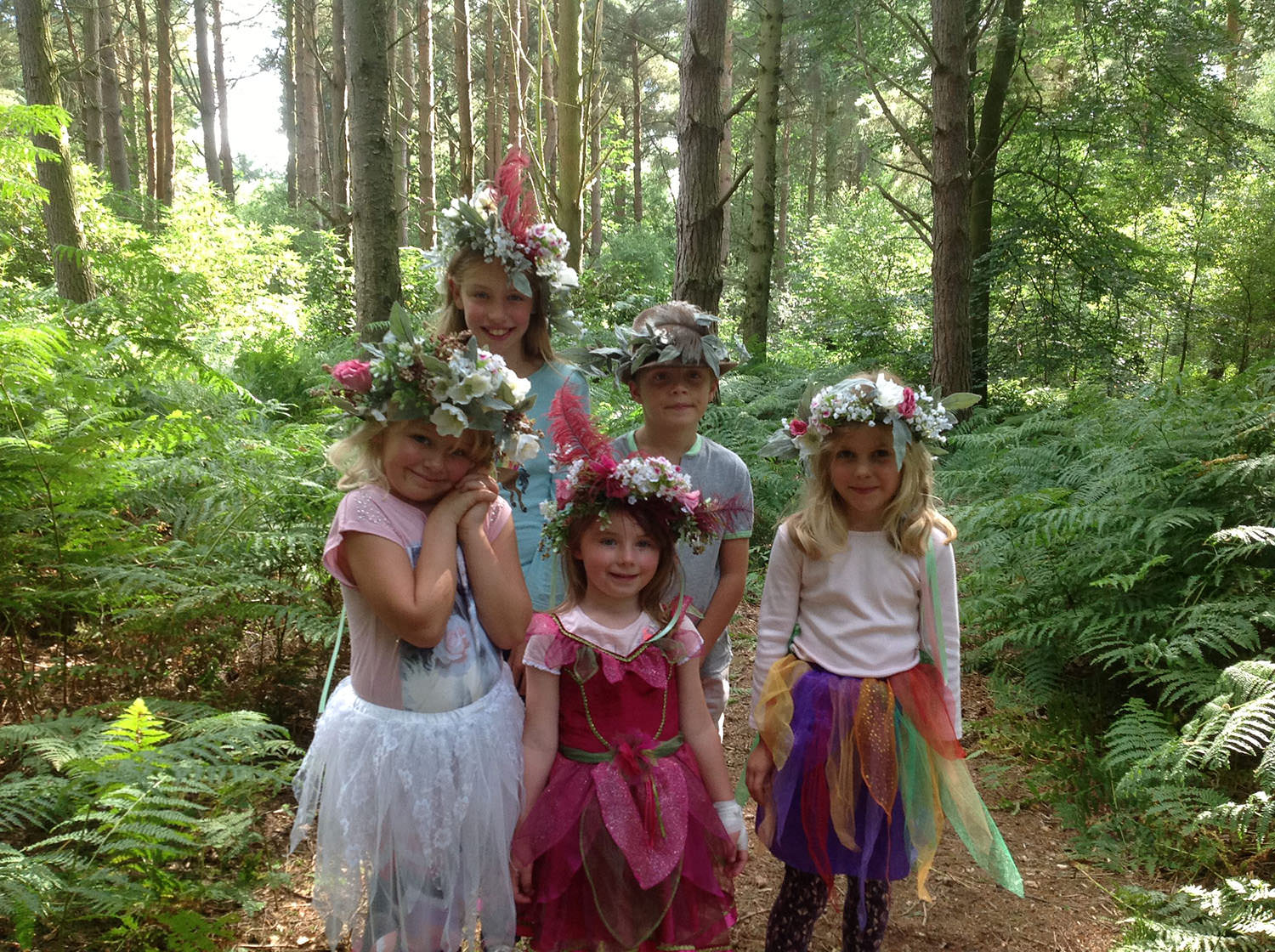 A group of small children stood in a wood dressed as faries