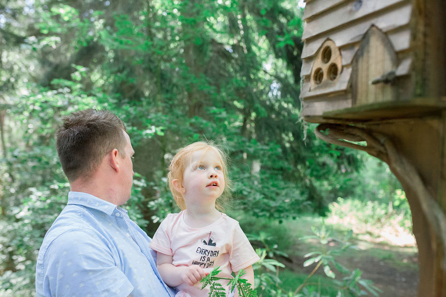 A small child looking in wonder at a fairy house.