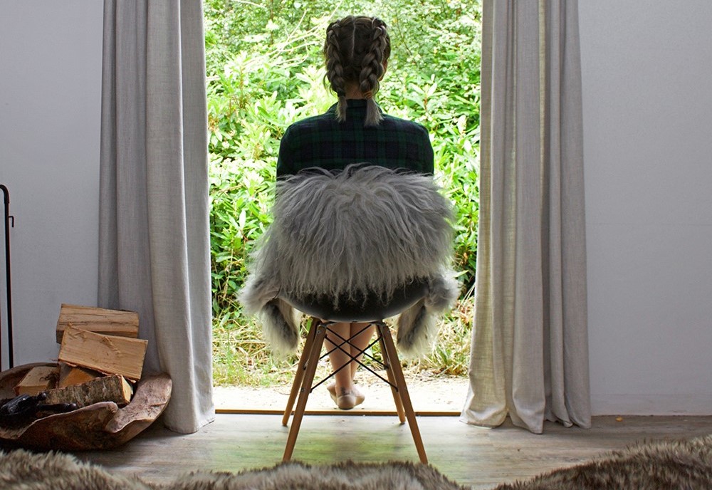 Girl sitting in a chair, looking out at the woods