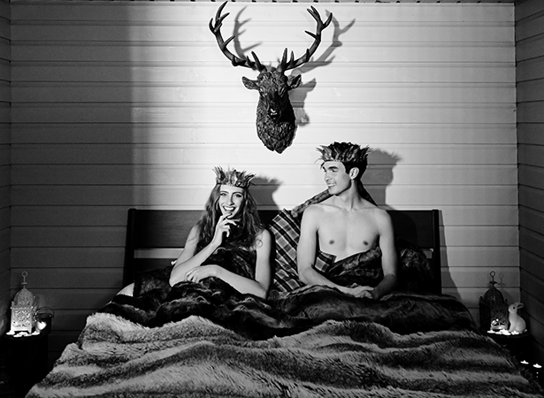 Two people laid in a bed with crowns on